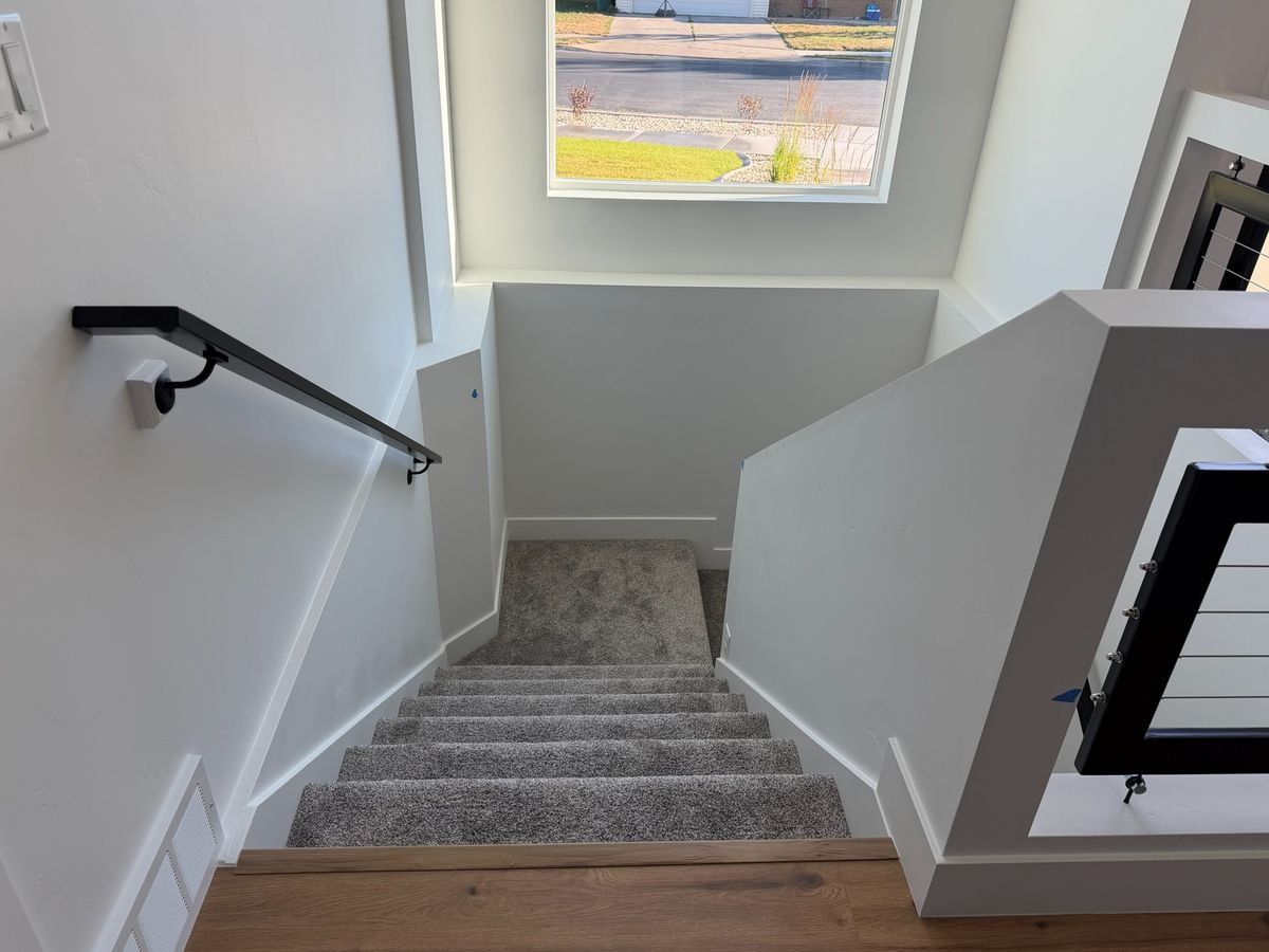 Before: a carpeted stairwell seen from the wood-floored landing, black handrail, no lift yet