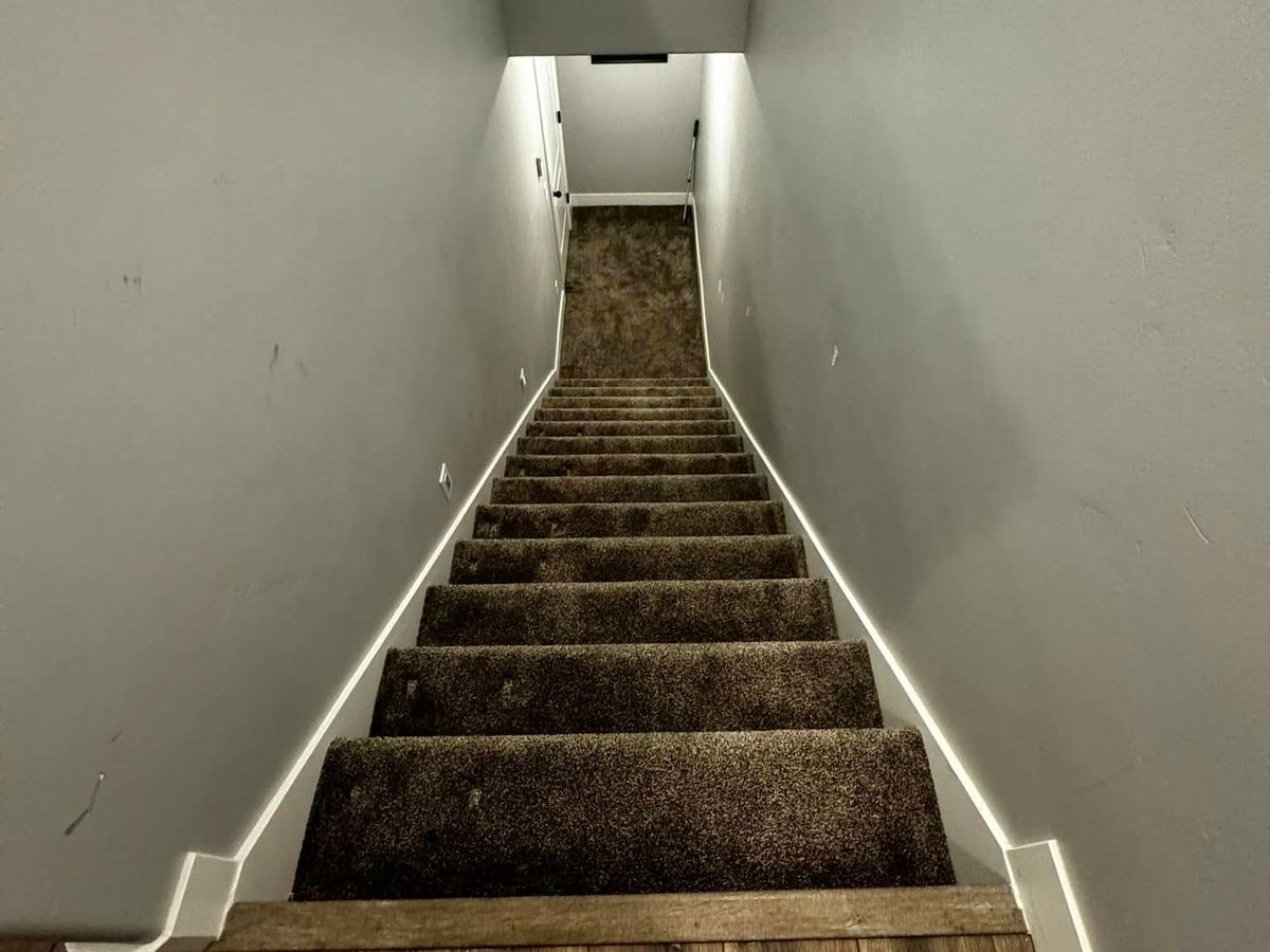 The same carpeted basement staircase before the stair lift was installed
