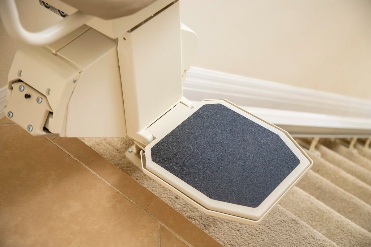Wide footrest of a Harmar SL600HD stair lift above carpeted steps